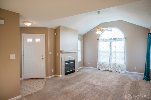 unfurnished living room featuring a tile fireplace, light colored carpet, ceiling fan, and lofted ceiling