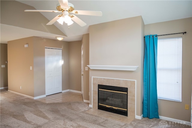 unfurnished living room with a tiled fireplace, ceiling fan, light colored carpet, and lofted ceiling