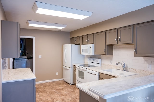 kitchen featuring kitchen peninsula, tasteful backsplash, white appliances, sink, and washer and dryer