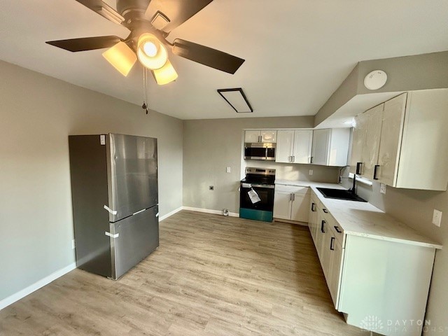 kitchen with white cabinetry, sink, ceiling fan, light hardwood / wood-style flooring, and appliances with stainless steel finishes