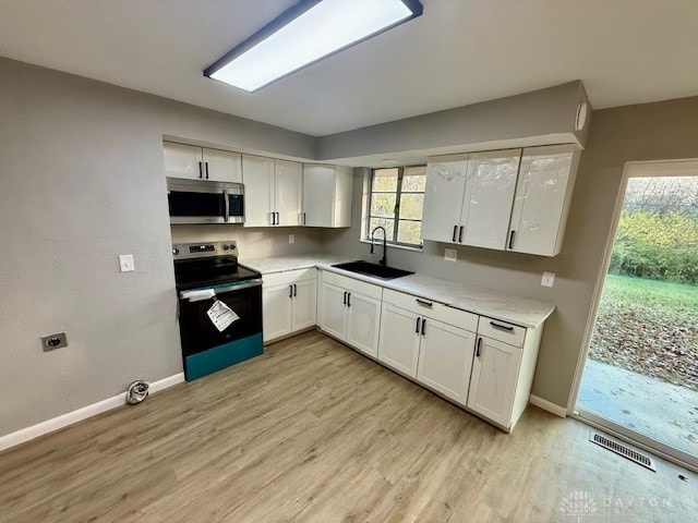 kitchen featuring white cabinets, appliances with stainless steel finishes, light hardwood / wood-style flooring, and sink