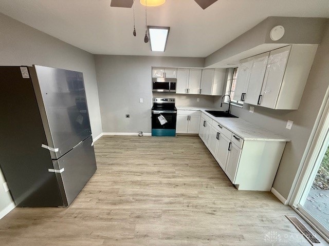 kitchen featuring white cabinetry, sink, ceiling fan, light hardwood / wood-style flooring, and appliances with stainless steel finishes