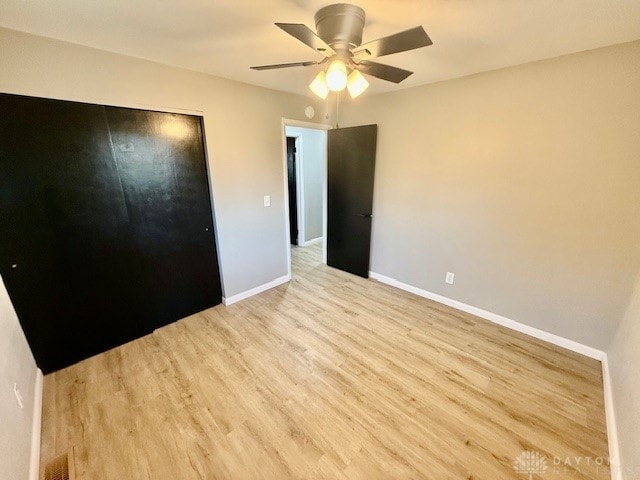 unfurnished bedroom featuring ceiling fan, light wood-type flooring, and a closet