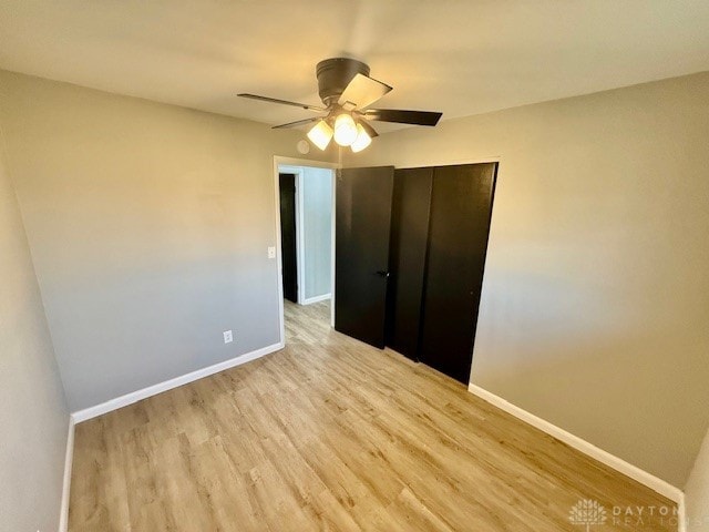 unfurnished bedroom with a closet, light hardwood / wood-style floors, and ceiling fan