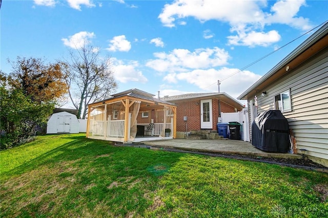 back of property with a lawn, a patio, and a storage unit