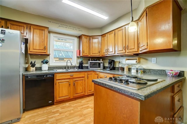 kitchen with stainless steel appliances, light hardwood / wood-style flooring, hanging light fixtures, and sink