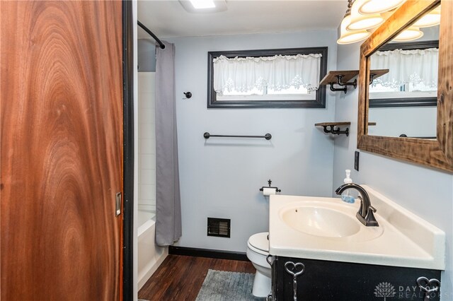 full bathroom featuring hardwood / wood-style flooring, vanity, shower / bath combination with curtain, and toilet