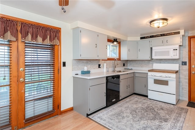 kitchen with gray cabinetry, white appliances, sink, and a wealth of natural light