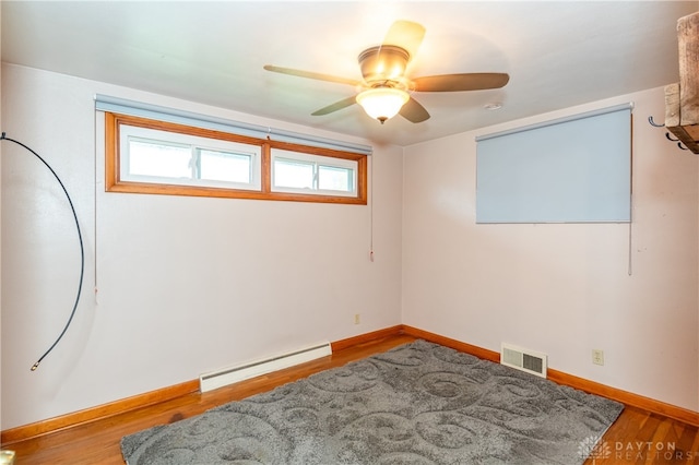 spare room with ceiling fan, light wood-type flooring, and baseboard heating