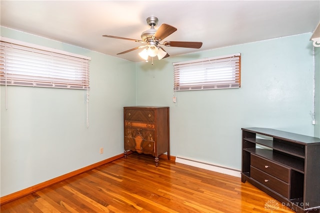 unfurnished room with ceiling fan, light wood-type flooring, and a baseboard heating unit