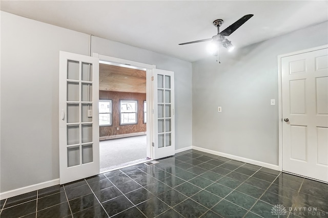 unfurnished room with french doors, dark tile patterned flooring, and ceiling fan