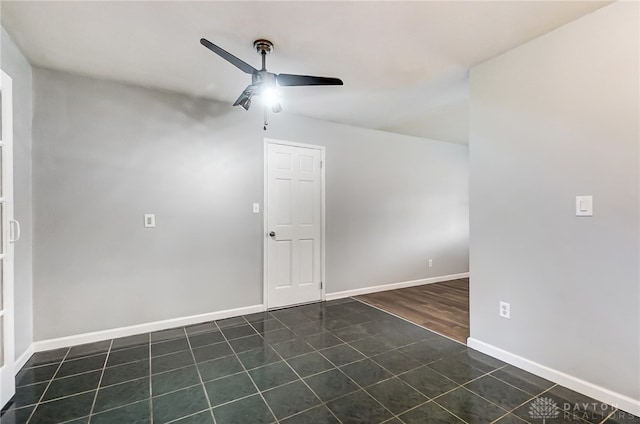 empty room featuring ceiling fan and dark tile patterned flooring