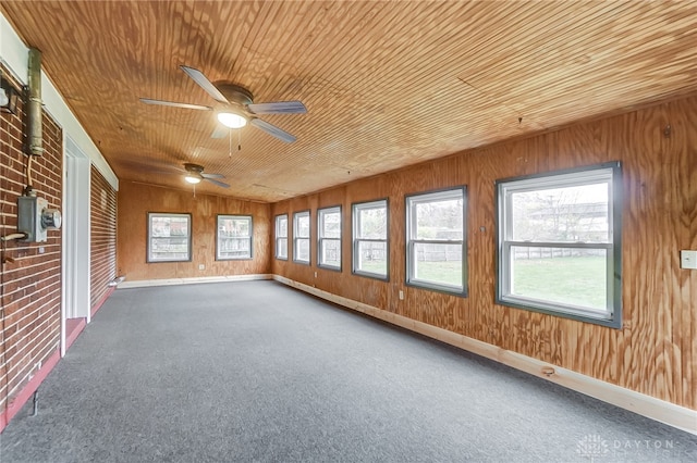 unfurnished sunroom featuring ceiling fan, a healthy amount of sunlight, and wooden ceiling