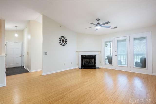 unfurnished living room with hardwood / wood-style flooring, ceiling fan, a premium fireplace, and vaulted ceiling