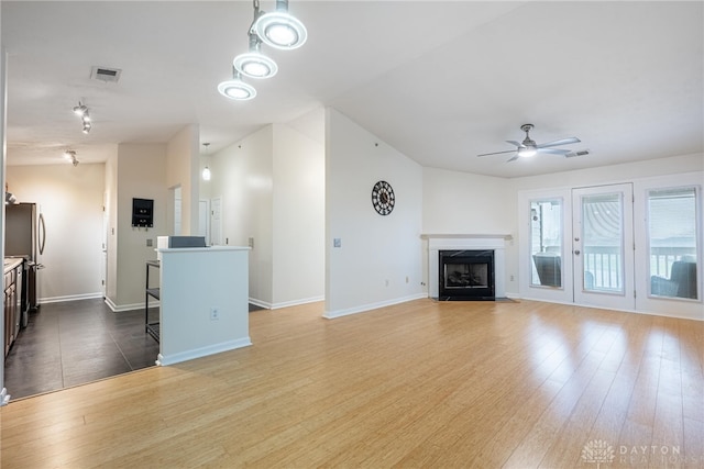 unfurnished living room featuring a premium fireplace, ceiling fan, and wood-type flooring