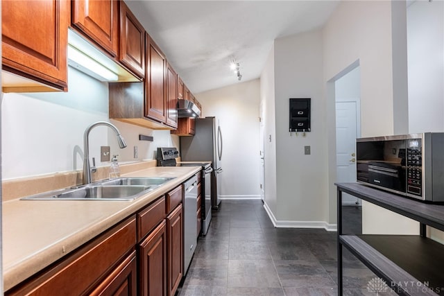 kitchen featuring appliances with stainless steel finishes, vaulted ceiling, dark tile patterned floors, and sink