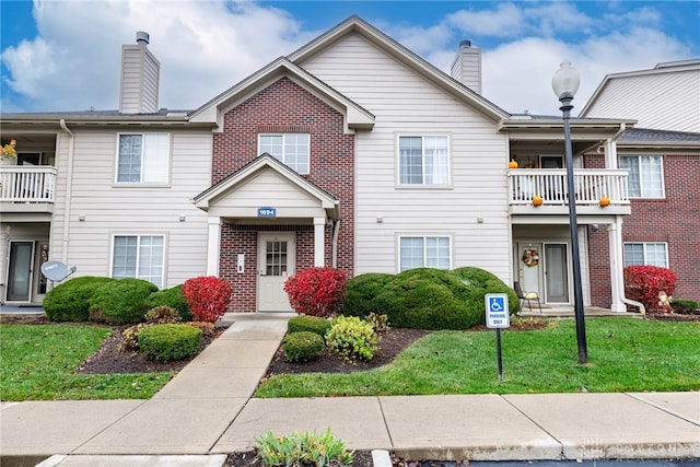 view of property with a front yard and a balcony