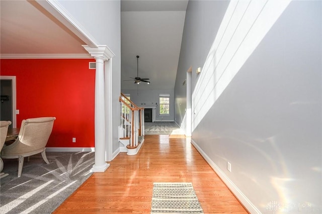 foyer entrance featuring ceiling fan, ornamental molding, light hardwood / wood-style flooring, and ornate columns