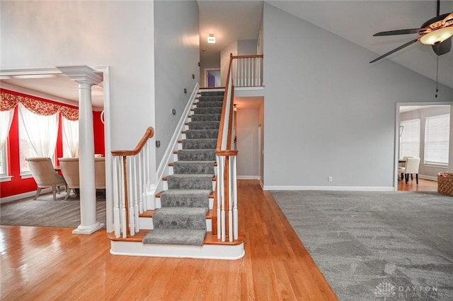 stairs featuring ceiling fan, high vaulted ceiling, hardwood / wood-style floors, and ornate columns