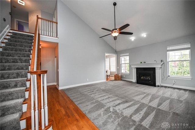 unfurnished living room with dark carpet, high vaulted ceiling, and ceiling fan