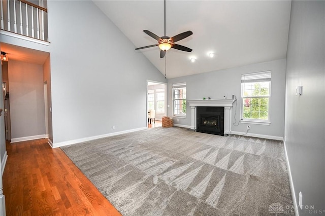 unfurnished living room featuring carpet floors, high vaulted ceiling, and ceiling fan