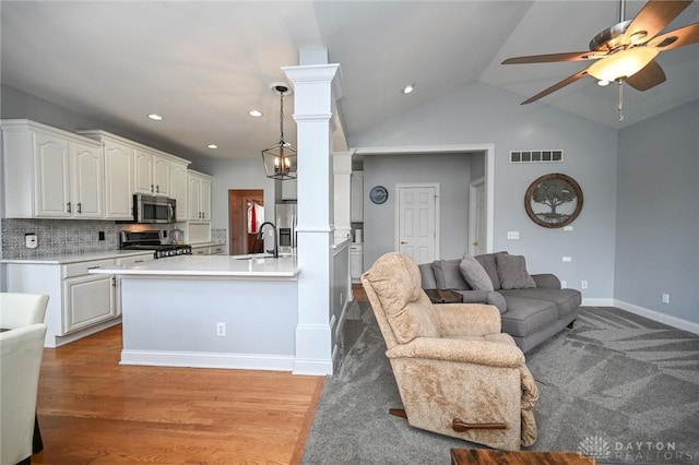 kitchen with appliances with stainless steel finishes, decorative light fixtures, tasteful backsplash, sink, and white cabinets