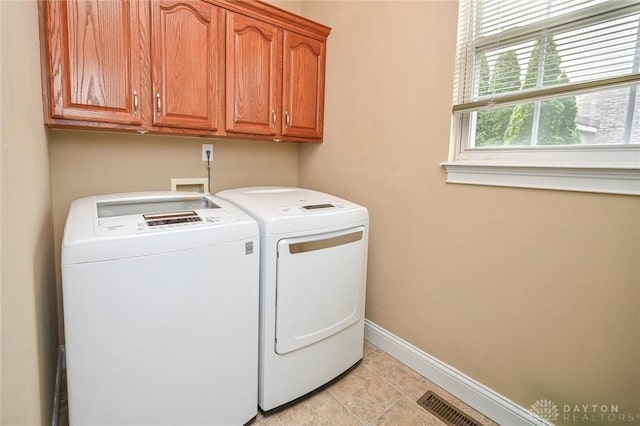 clothes washing area featuring independent washer and dryer, cabinets, and light tile patterned floors