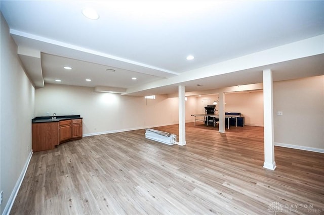 basement with sink and light wood-type flooring