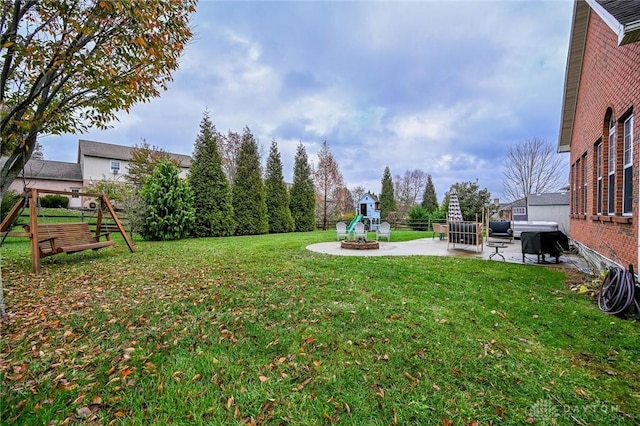 view of yard featuring a playground, a patio area, and an outdoor fire pit