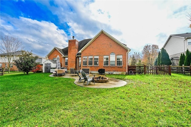 back of property featuring a yard, a patio area, a shed, and an outdoor fire pit