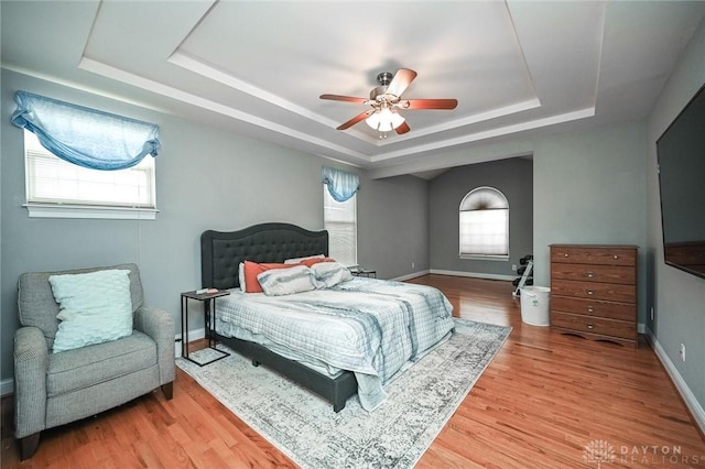 bedroom featuring hardwood / wood-style floors, a raised ceiling, and ceiling fan