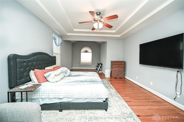 bedroom with hardwood / wood-style floors, a raised ceiling, and ceiling fan