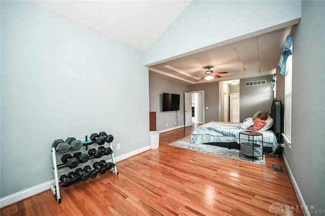 bedroom with hardwood / wood-style flooring, ceiling fan, lofted ceiling, and a raised ceiling