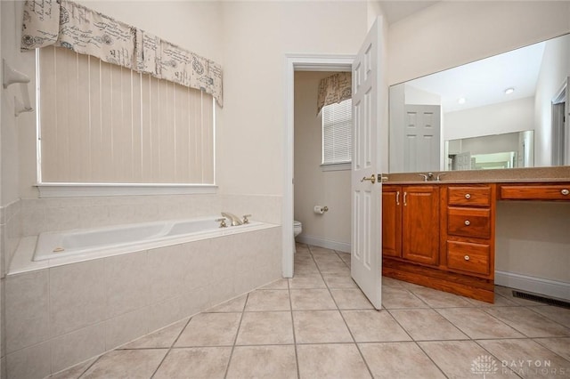 bathroom with vanity, toilet, tile patterned flooring, and tiled bath