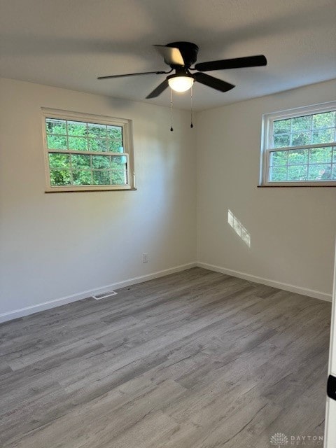 spare room with plenty of natural light, light hardwood / wood-style floors, and ceiling fan