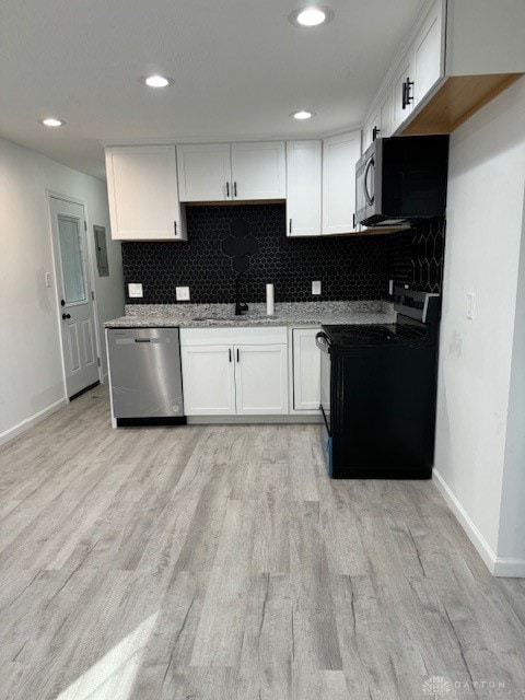 kitchen featuring tasteful backsplash, light stone counters, light hardwood / wood-style flooring, white cabinets, and appliances with stainless steel finishes