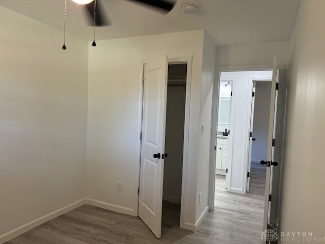 unfurnished bedroom with ceiling fan, a closet, and light wood-type flooring