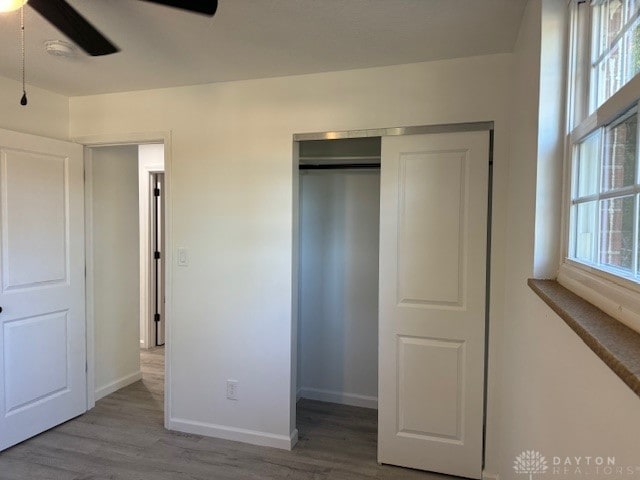 unfurnished bedroom with hardwood / wood-style floors, ceiling fan, and a closet