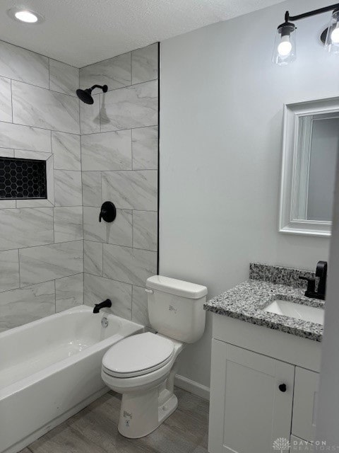 full bathroom with wood-type flooring, a textured ceiling, toilet, vanity, and tiled shower / bath