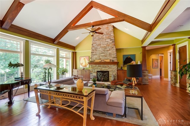 living room featuring beamed ceiling, wood-type flooring, and a stone fireplace