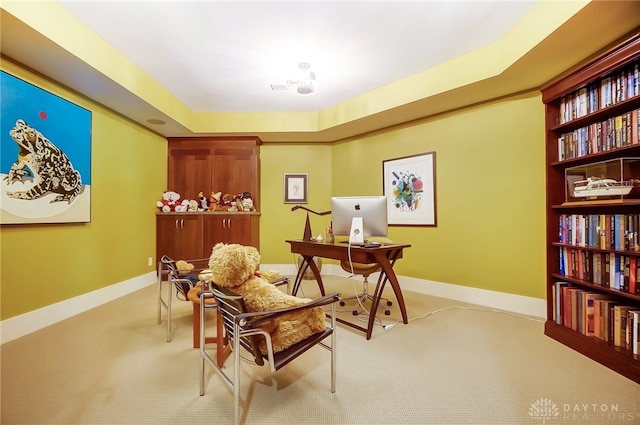 office area with light carpet and a tray ceiling