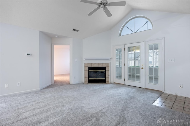 unfurnished living room with ceiling fan, carpet floors, high vaulted ceiling, and a tiled fireplace