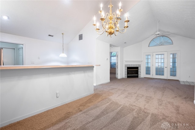 unfurnished living room with carpet flooring, ceiling fan with notable chandelier, lofted ceiling, and a tiled fireplace