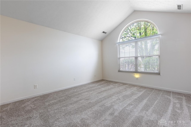 carpeted empty room with lofted ceiling