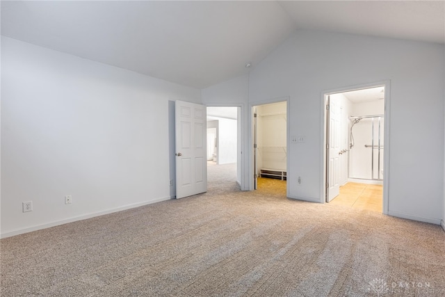 unfurnished bedroom with a walk in closet, light carpet, a closet, and lofted ceiling