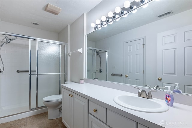 bathroom with tile patterned floors, vanity, an enclosed shower, and toilet