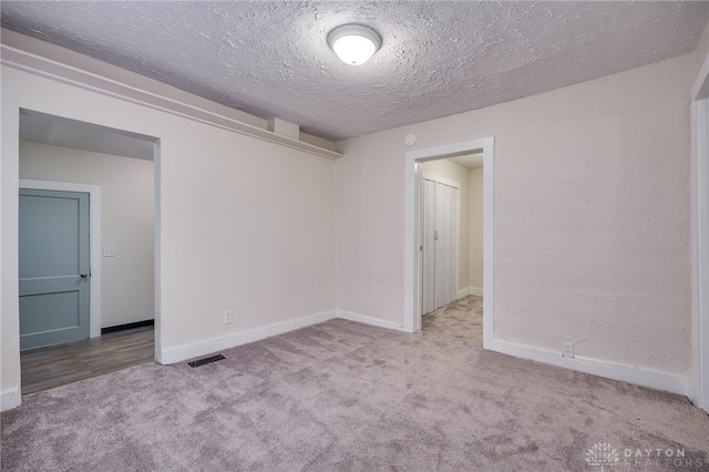 spare room with light carpet and a textured ceiling