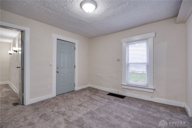 unfurnished room featuring a textured ceiling and light carpet