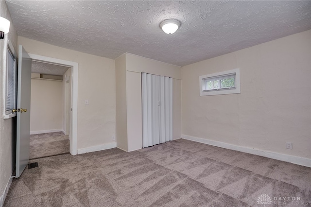 unfurnished bedroom featuring light colored carpet and a textured ceiling