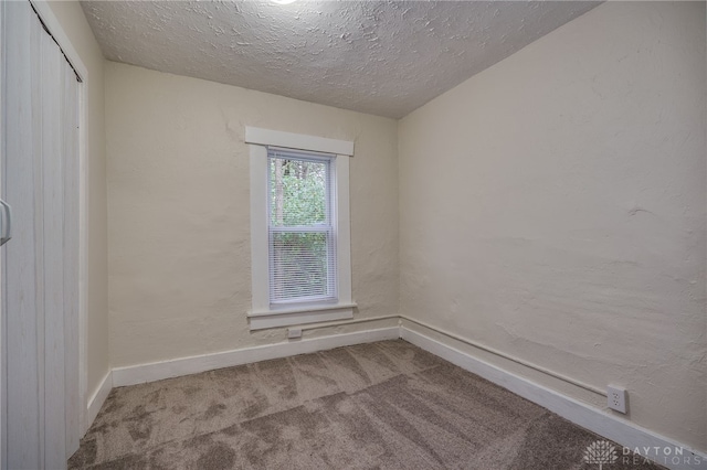 carpeted empty room with a textured ceiling